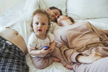 Niedliche Tochter sitzt inmitten von Mutter und Vater tun Romantik auf Bett zu Hause - VPIF04297