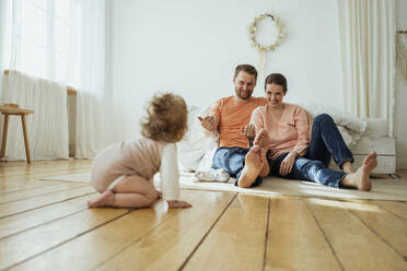 Smiling parents calling daughter crawling at home - VPIF04345