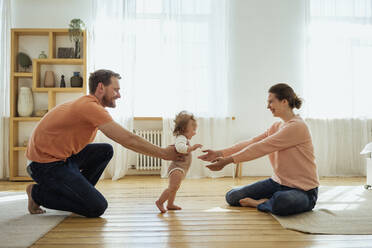 Parents helping daughter walking at home - VPIF04348