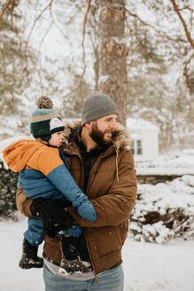 Kanada, Ontario, Vater hält kleinen Jungen (12-17 Monate) an einem Wintertag - ISF24626