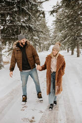 Kanada, Ontario, Lächelndes Paar hält sich bei einem Winterspaziergang an den Händen - ISF24635