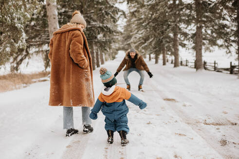 Kanada, Ontario, Eltern mit kleinem Jungen (12-17 Monate) machen einen Winterspaziergang - ISF24637