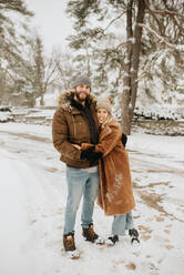 Kanada, Ontario, Umarmendes Paar auf verschneiter Straße stehend - ISF24639