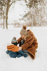 Kanada, Ontario, Mutter und kleiner Junge (12-17 Monate) spielen im Schnee - ISF24644