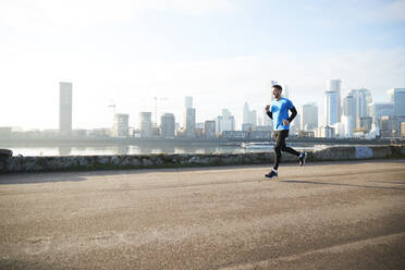 UK, London, Jogger läuft mit der Skyline der Innenstadt im Hintergrund - ISF24669