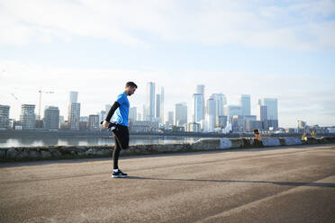 UK, London, Jogger beim Stretching mit der Skyline der Innenstadt im Hintergrund - ISF24670