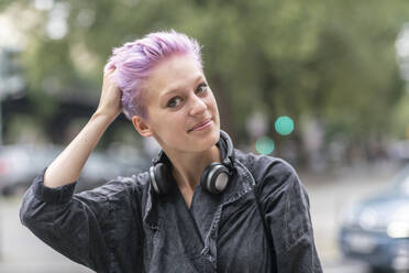 Happy non-binary female hipster standing on the road in city stock photo