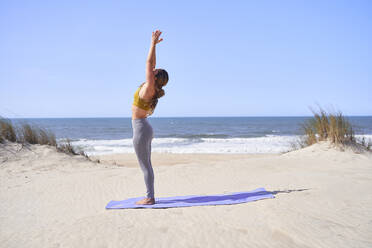 Junges Mädchen macht Yoga-Position am Strand am Morgen. - CAVF94437