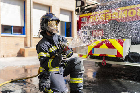 Feuerwehrmann gießt Wasser, um ein Feuer zu löschen - CAVF94510