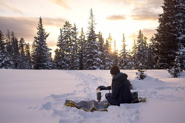 Junge Frau bei der Zubereitung des Abendessens beim Wintercamping bei Sonnenuntergang - CAVF94601