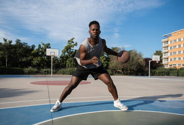 African American sportsman dribbling basketball ball - CAVF94615