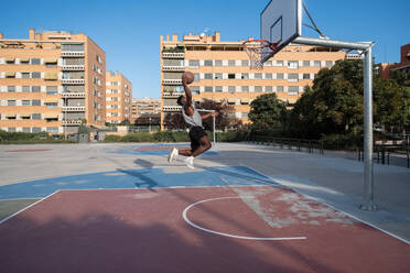 Black man scoring ball during basketball match - CAVF94616