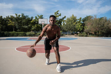 Schwarzer Basketballspieler ohne Hemd dribbelt Ball - CAVF94617