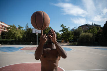 Ethnischer Basketballspieler, der den Ball auf dem Finger dreht - CAVF94619