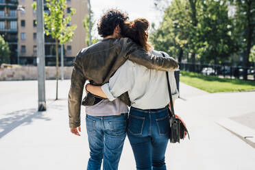 Couple with arms around walking on footpath during sunny day - MEUF03189