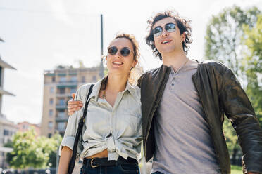 Smiling boyfriend with arm around girlfriend during sunny day - MEUF03190
