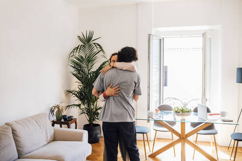 Paar umarmt sich gegenseitig, während es zu Hause steht - MEUF03226