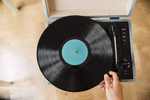 Musician holding record on turntable at home - EGHF00072
