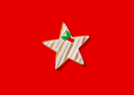 Star shaped Christmas cookie against vibrant red background - FLMF00575