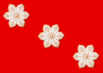 Three snowflake shaped Christmas cookies against vibrant red background - FLMF00583