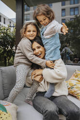 Glückliche Mutter hat Spaß mit Töchtern auf dem Sofa im Hinterhof - MFF08233