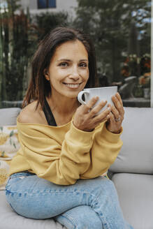 Woman having coffee on sofa at backyard - MFF08237