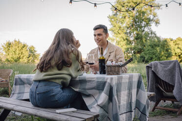 Smiling young man looking girlfriend sitting on bench - VPIF04412