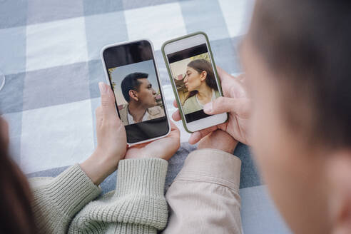 Junges Paar hält Smartphones mit Fotos - VPIF04421