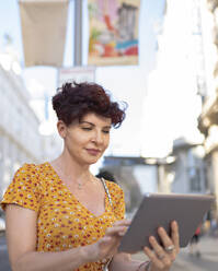 Ältere Frau benutzt digitales Tablet in der Stadt - JCCMF03101