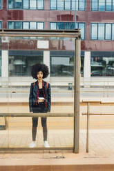 Woman standing behind glass wall at tram station - MEUF03317