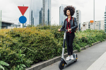 Young woman riding electric push scooter in city - MEUF03326