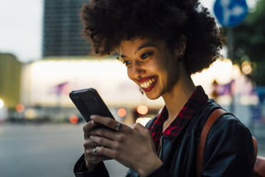 Smiling woman using smart phone at dusk - MEUF03386