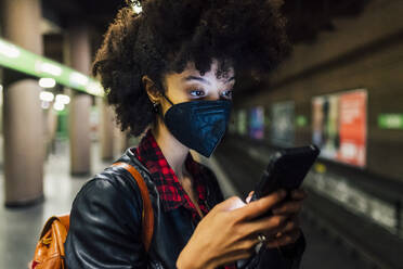 Young woman with face mask using mobile phone at subway - MEUF03389