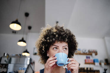 Frau schaut beim Kaffeetrinken im Café weg - ASGF00739