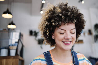 Young woman with eyes closed smiling at cafe - ASGF00742