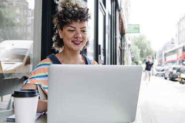 Frau benutzt Laptop in einem Straßencafé - ASGF00746