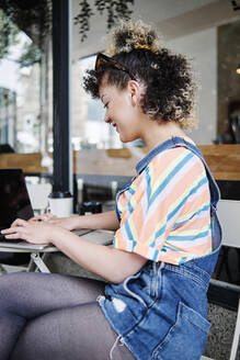 Frau benutzt Laptop in einem Straßencafé - ASGF00747