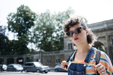 Young woman wearing sunglasses and backpack on sunny day - ASGF00753