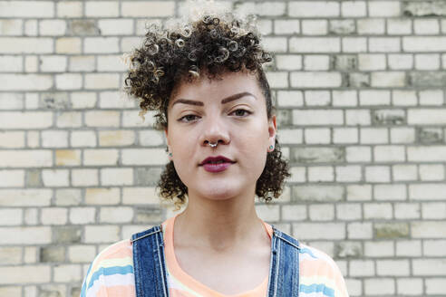 Woman wearing nose ring in front of brick wall - ASGF00756