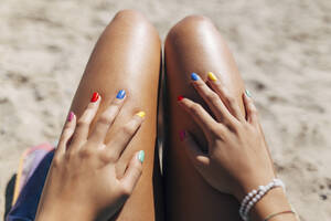 Frau mit buntem Nagellack genießt sonnigen Tag am Strand - EGHF00077