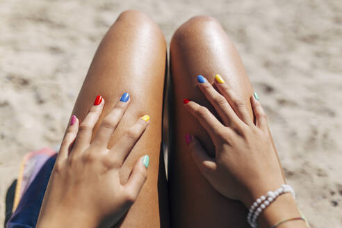 Woman with colorful nail polish enjoying sunny day at beach - EGHF00077