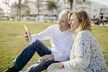 Glückliches reifes Paar macht Videoanruf durch digitale Tablet während des sonnigen Tages - GMCF00146