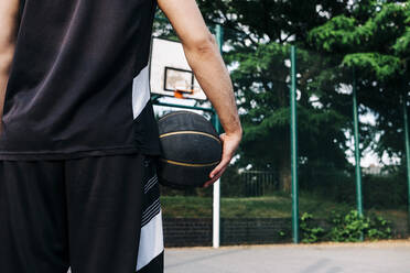 Athlete holding basketball at sports court - ASGF00772