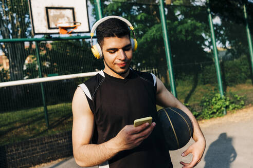 Basketballspieler hört Musik über Kopfhörer auf dem Spielfeld - ASGF00775
