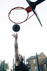 Junger Sportler spielt Basketball auf einem Sportplatz - ASGF00780