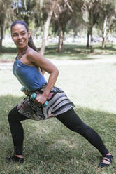 Young female athlete with dumbbell exercising at park - DSIF00466