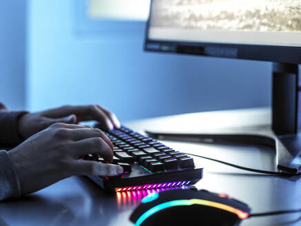 Jugendlicher, der ein Videospiel spielt und die Tastatur eines Computers am Tisch benutzt - ABRF00892