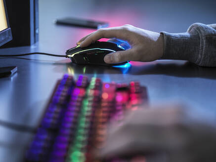 Boy using illuminated gaming mouse while playing video game - ABRF00896