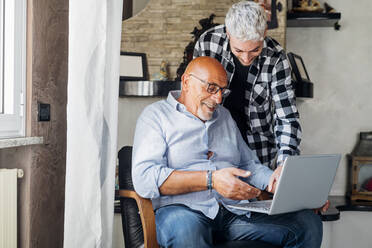 Father using laptop with son at home - MEUF03402