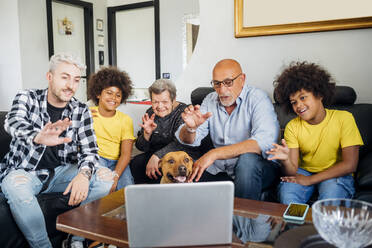 Begrüßung einer multiethnischen Familie während eines Videoanrufs auf dem Laptop zu Hause - MEUF03405